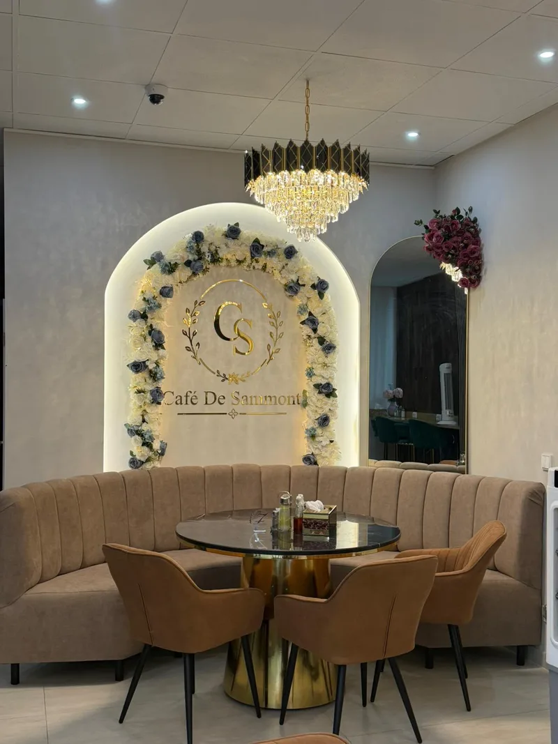Logo-Wand des Café de Sammont mit Blumendekoration und Kronleuchter